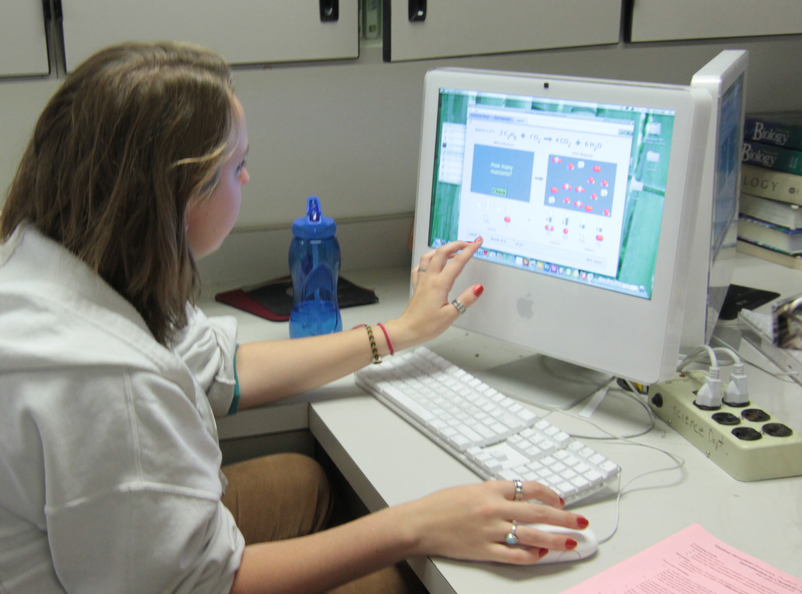 A student in a high school classroom exploring a simulation and discussing her observations with the others in her group.